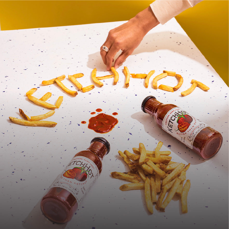 Two bottles of KetchHot on a table with fries arranged to spell out "KetchHot"